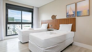 A hotel room with two beds, a large window with a city view, and two framed pictures on the wall. - WI-FI 350MB | 150m from Jurerê Beach #JA29 (Florianópolis)