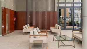 A modern lobby with seating arrangements, a glass coffee table, and a fire extinguisher. - WI-FI 350MB | 150m from Jurerê Beach #JA29 (Florianópolis)
