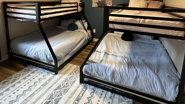 A room with two bunk beds, a ceiling fan, and a painting on the wall.