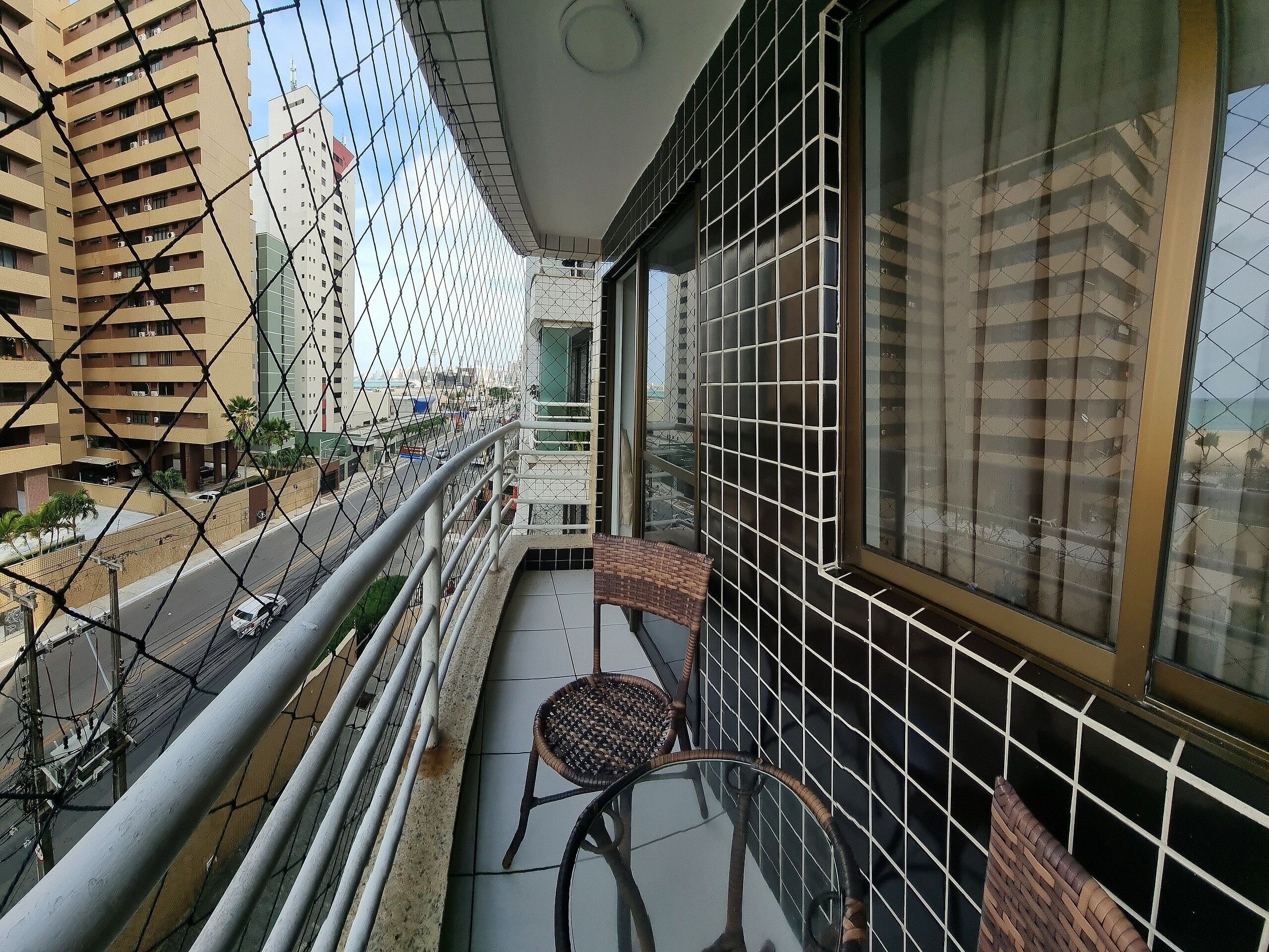 A balcony with a chair and a view of a city street.