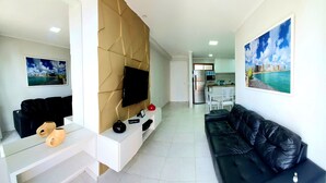 A modern living room with a black leather sofa, a white entertainment unit, and a mounted TV. - Atlantic Ocean by SOLEMAR (Fortaleza)
