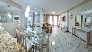 A modern living room with a glass dining table, a sofa, and a TV mounted on the wall. - Atlantic Ocean by SOLEMAR (Fortaleza)