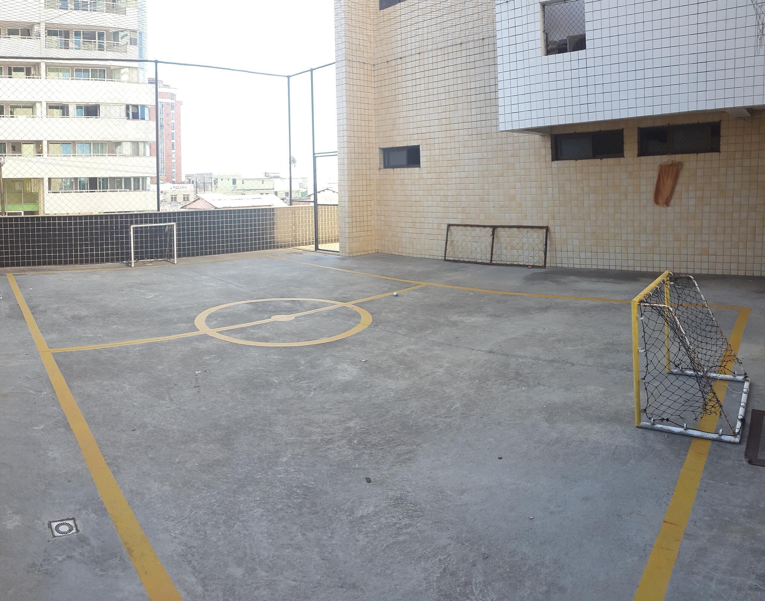Eine Basketballhalle mit Netz, gelben Linien und einer gefliesten Wand.