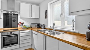 Een moderne keuken met witte kasten, een Bosch oven, een broodrooster en een spoelbak.