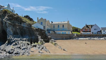 Un bâtiment situé sur la côte, avec une plage au premier plan.