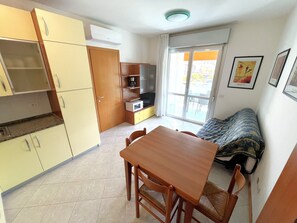 Una cucina compatta con un tavolo e sedie, un forno a microonde e una porta scorrevole in vetro che dà su un balcone.