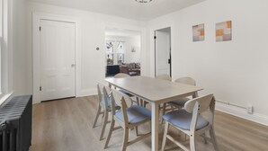 A dining area with a rectangular table and six chairs, a radiator, and a ceiling light fixture. - Modern 4 BR/2 Bath House near University of Rochester (Rochester)