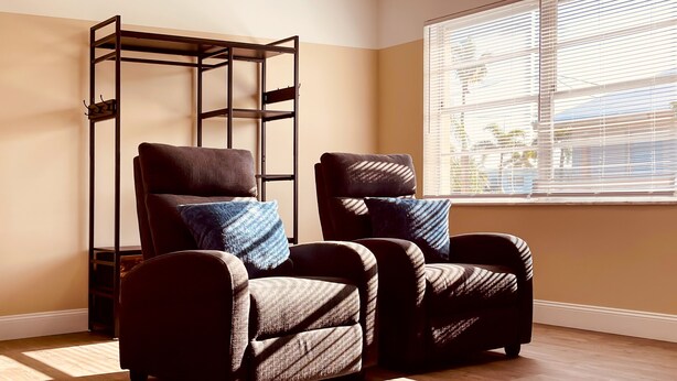 A room with two reclining chairs and a standing chair with a metal frame.