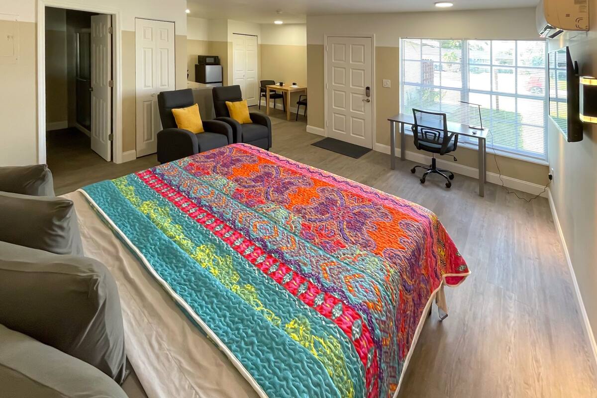 A bedroom with a large bed, a desk, and a chair.