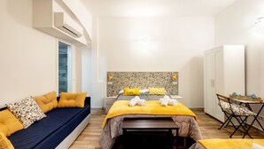 Een moderne slaapkamer met een bed, een bank, een eettafel en een kledingkast.