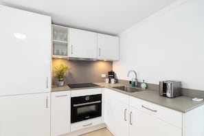 Eine moderne Küche mit weißen Schränken, einem Backofen, einer Kaffeemaschine und einem Toaster.