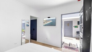 Un dormitorio con cama, una puerta que da a un balcón y un televisor en la pared.
