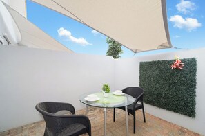 A glass table with chairs, a potted plant, and a wall-mounted decorative item in a covered outdoor area. - Charming 1BR w/ Shared Pool, near Aruba’s Beaches (Noord)