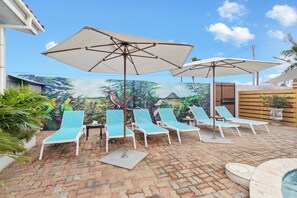 Ein Poolbereich mit Liegestühlen, Sonnenschirmen, Wandgemälde und einem Whirlpool.