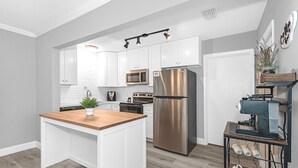 A modern kitchen with white cabinetry, stainless steel appliances, and a wooden island.