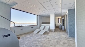 Un balcon spacieux offrant une vue dégagée sur l’eau, un coin salon avec des fauteuils, et un design moderne avec des murs et un sol carrelés.