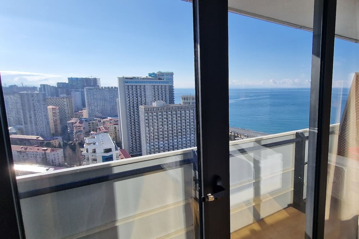 A balcony with a cityscape view, including high-rise buildings and a body of water.