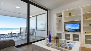 A modern living room with a glass coffee table, a sofa, and a TV on a white shelf. - La Terraza de Salinetas By VillaGranCanaria (Telde)