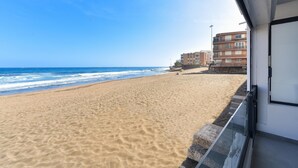 A beach with a clear view of the ocean and a building with multiple balconies. - La Terraza de Salinetas By VillaGranCanaria (Telde)