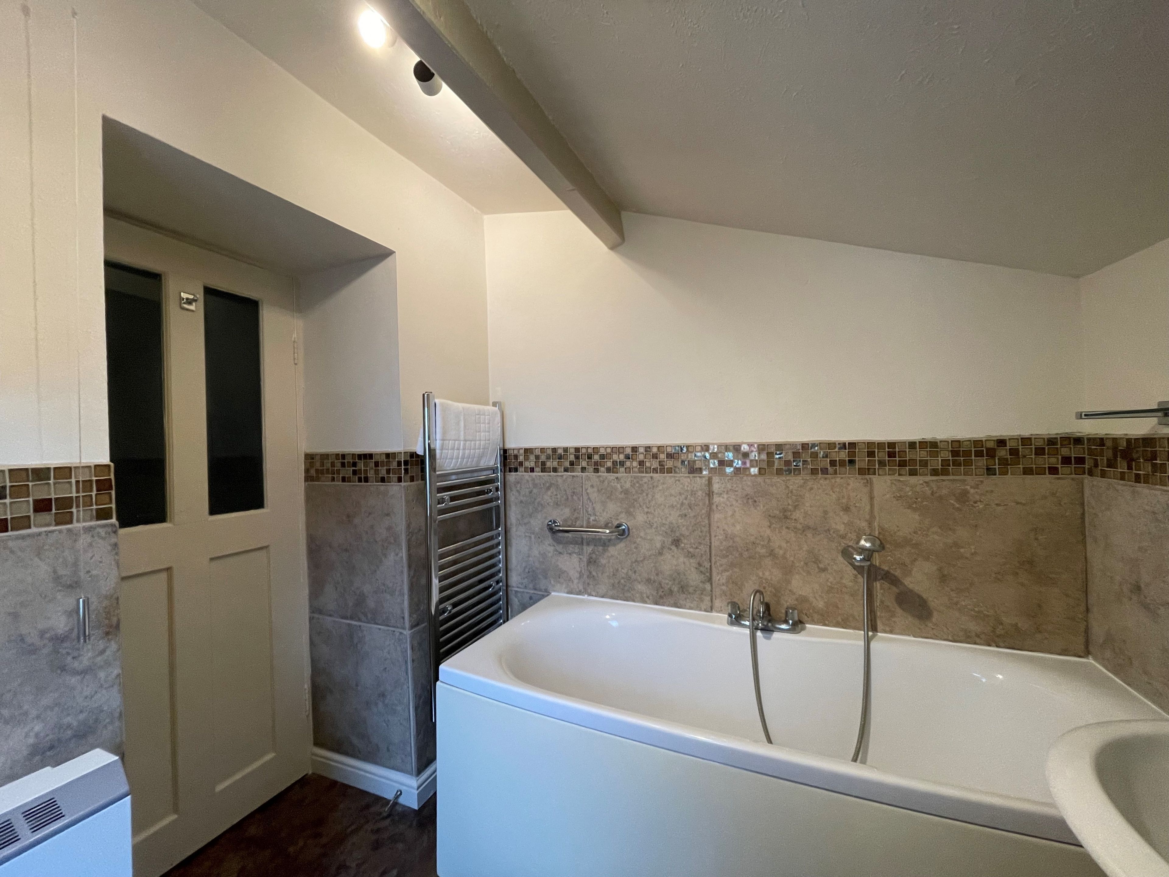 Une salle de bain équipée d'une baignoire, d'un porte-serviettes et d'un espace douche.