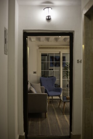 A hallway leading to a room with a blue armchair, a sofa, and a small table. - Smart home Madinaty - The butterfly (New Cairo)