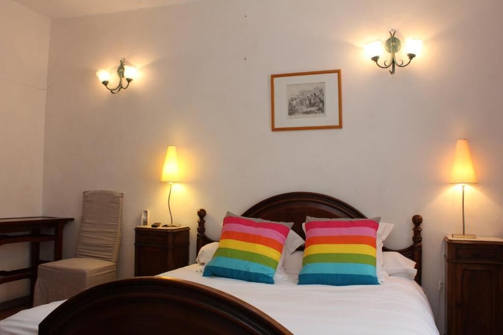 Un dormitorio con cama de madera, dos lámparas de noche, una silla y un cuadro en la pared.