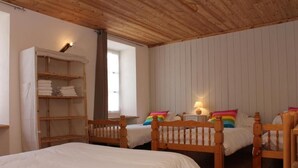 Une chambre avec deux lits en bois, une armoire en bois et une fenêtre avec des rideaux.