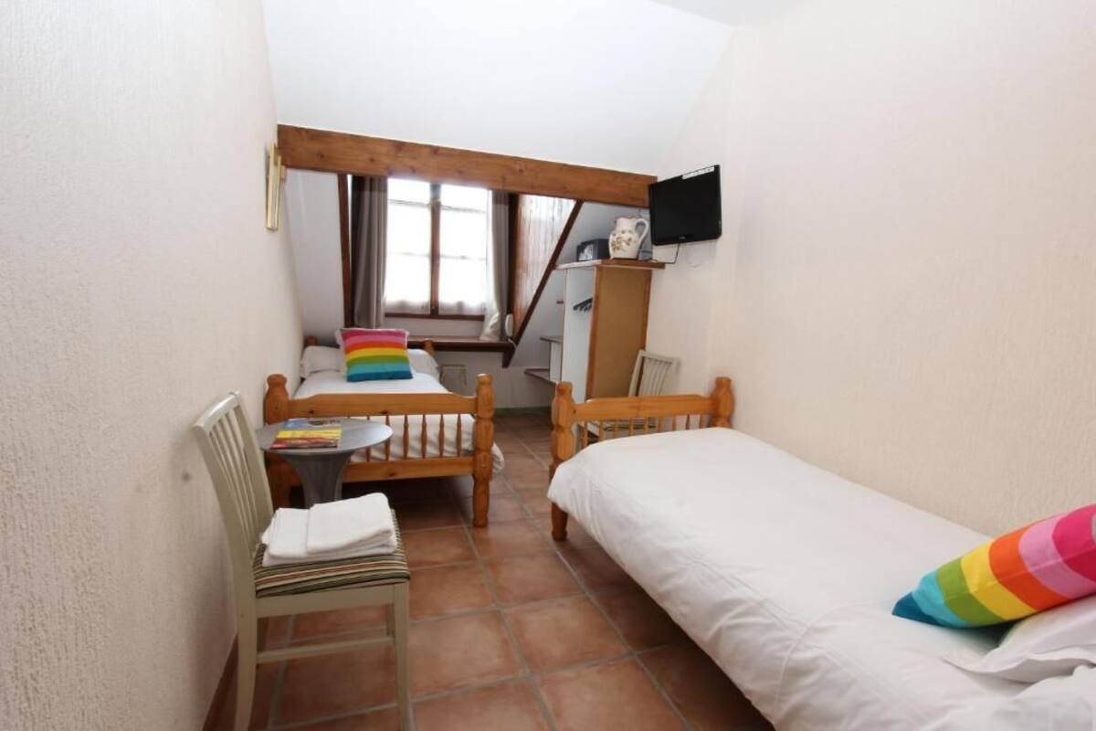 Una habitación pequeña y acogedora con cama, una silla, una mesa y ventana.
