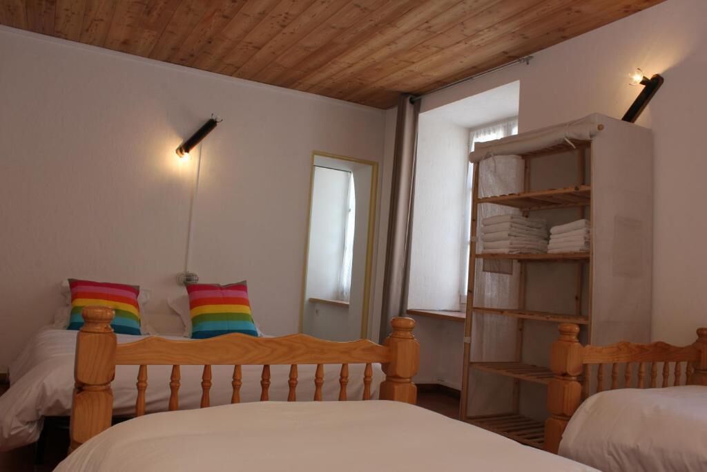 A bedroom with two wooden beds, a wardrobe, and a mirror.
