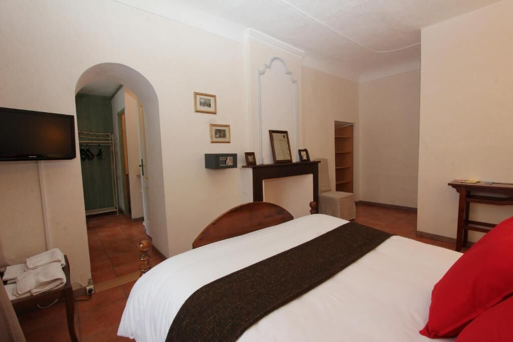 A hotel room with a bed, a TV mounted on the wall, a mirror, and a small table.