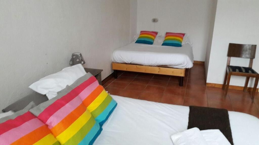 Un dormitorio con cama, dos almohadas, una silla y una mesita de noche.