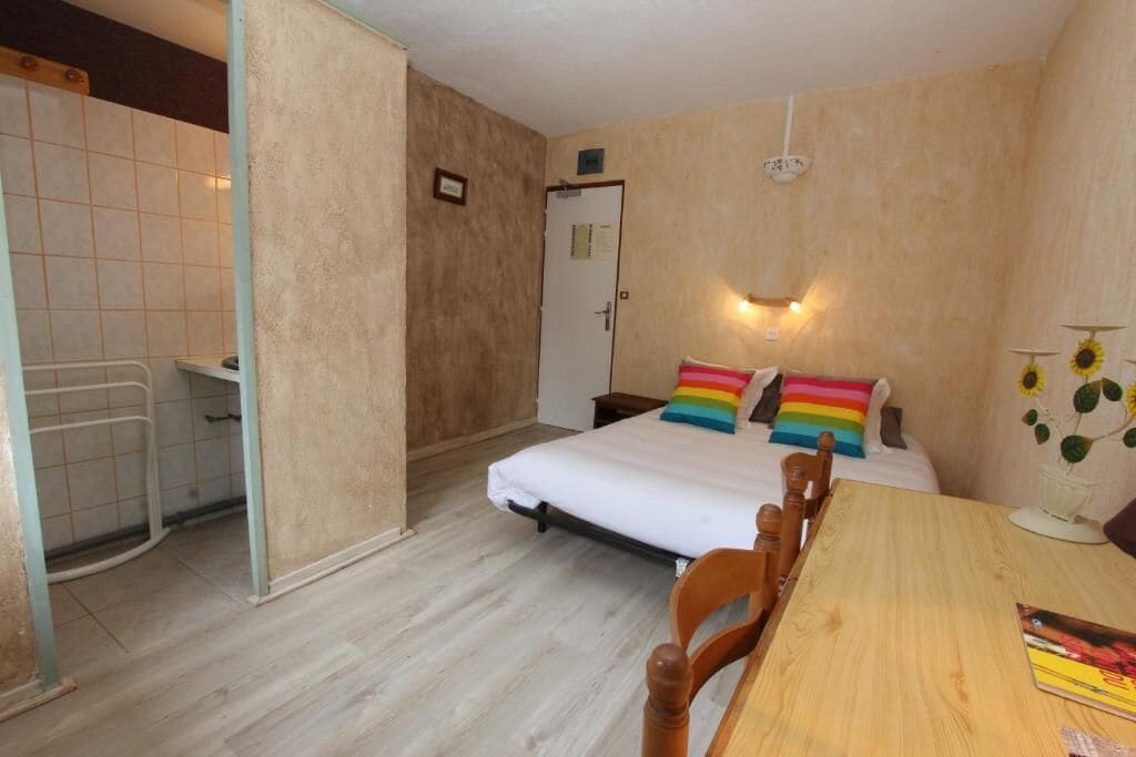 A bedroom with a bed, a wooden table, and a chair.
