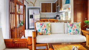 A modern living room with a sofa, wooden furniture, and a kitchen in the background. - DELUXE PENTHOUSE VILLA THE PALMS (El Gariton)