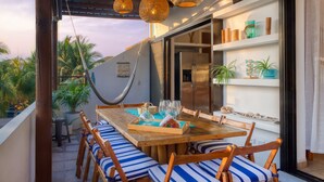 A wooden dining table with striped cushions, a hanging hammock, and a glass tray with drinks and snacks. - DELUXE PENTHOUSE VILLA THE PALMS (El Gariton)