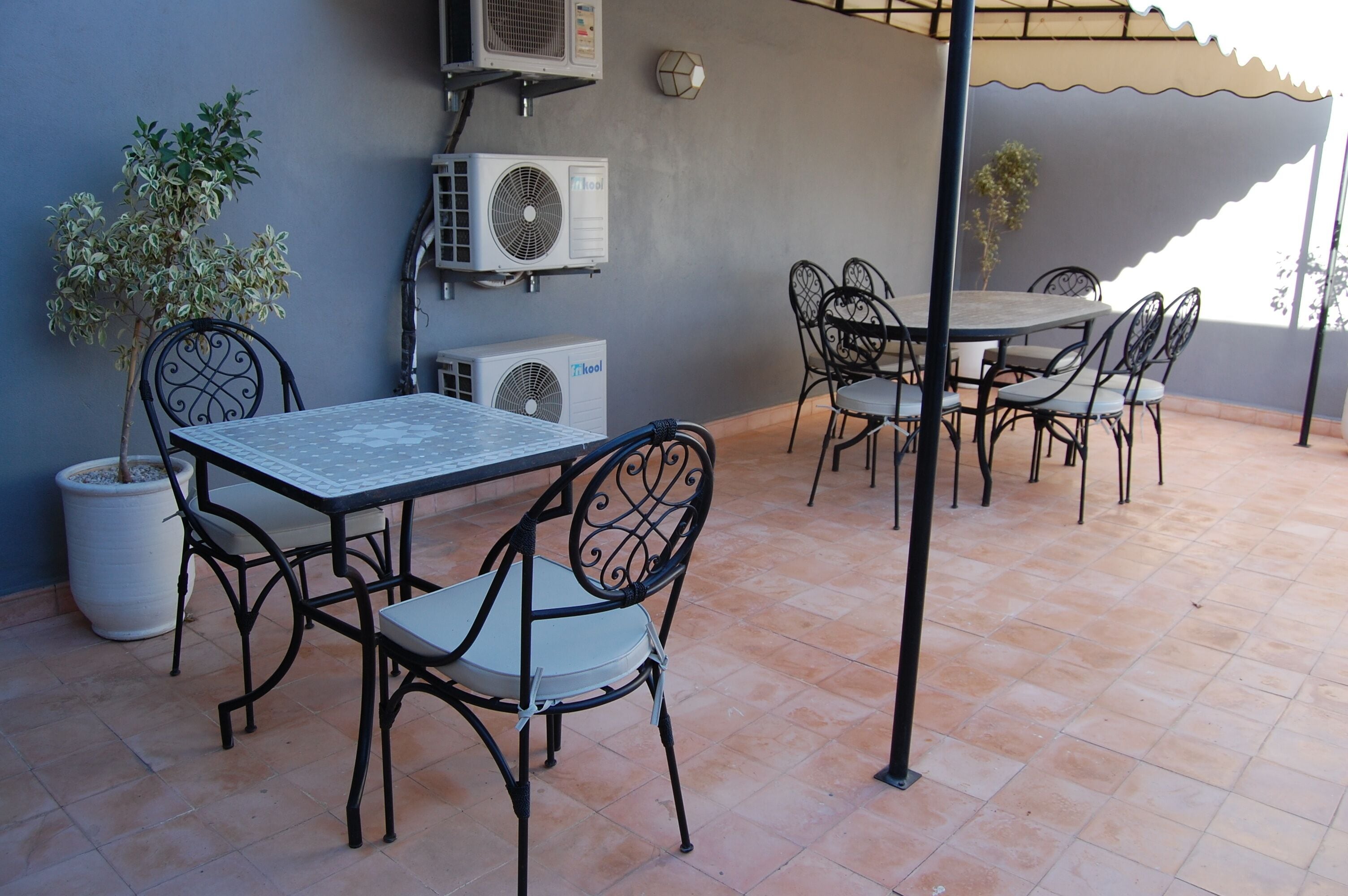 An outdoor patio with a table and chairs, air conditioning units, and potted plants.