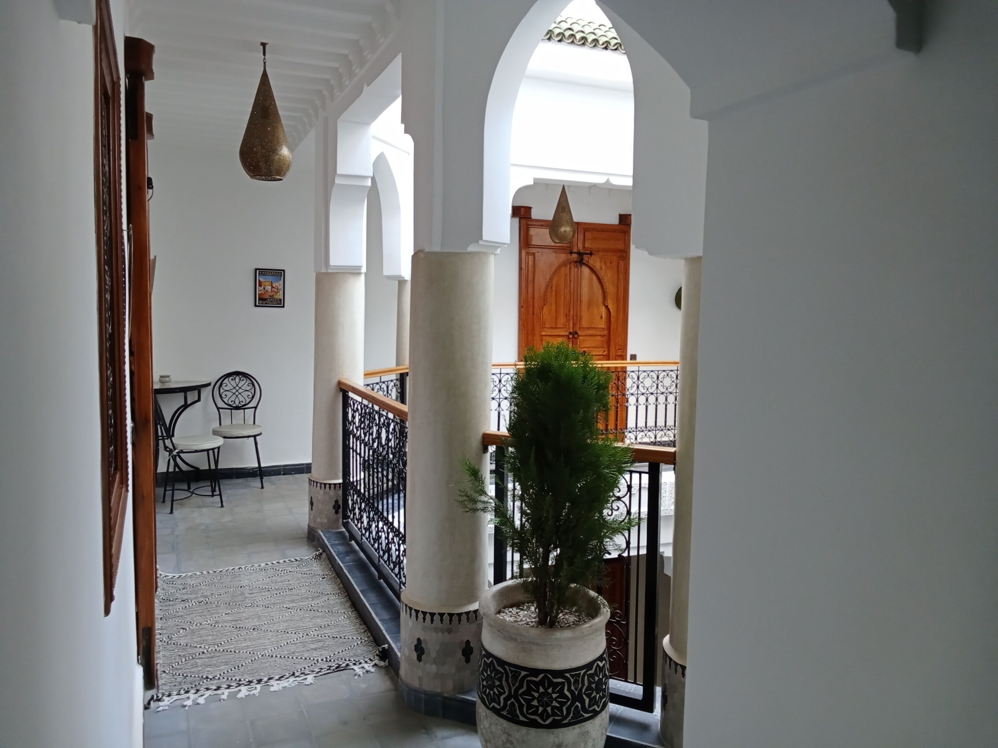 Um corredor com escada, planta em vaso e porta de madeira.