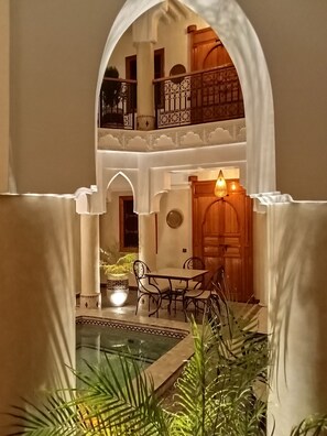 An indoor courtyard with a pool, seating area, and a wooden door. - Riad Orient Palace (Marrakech)