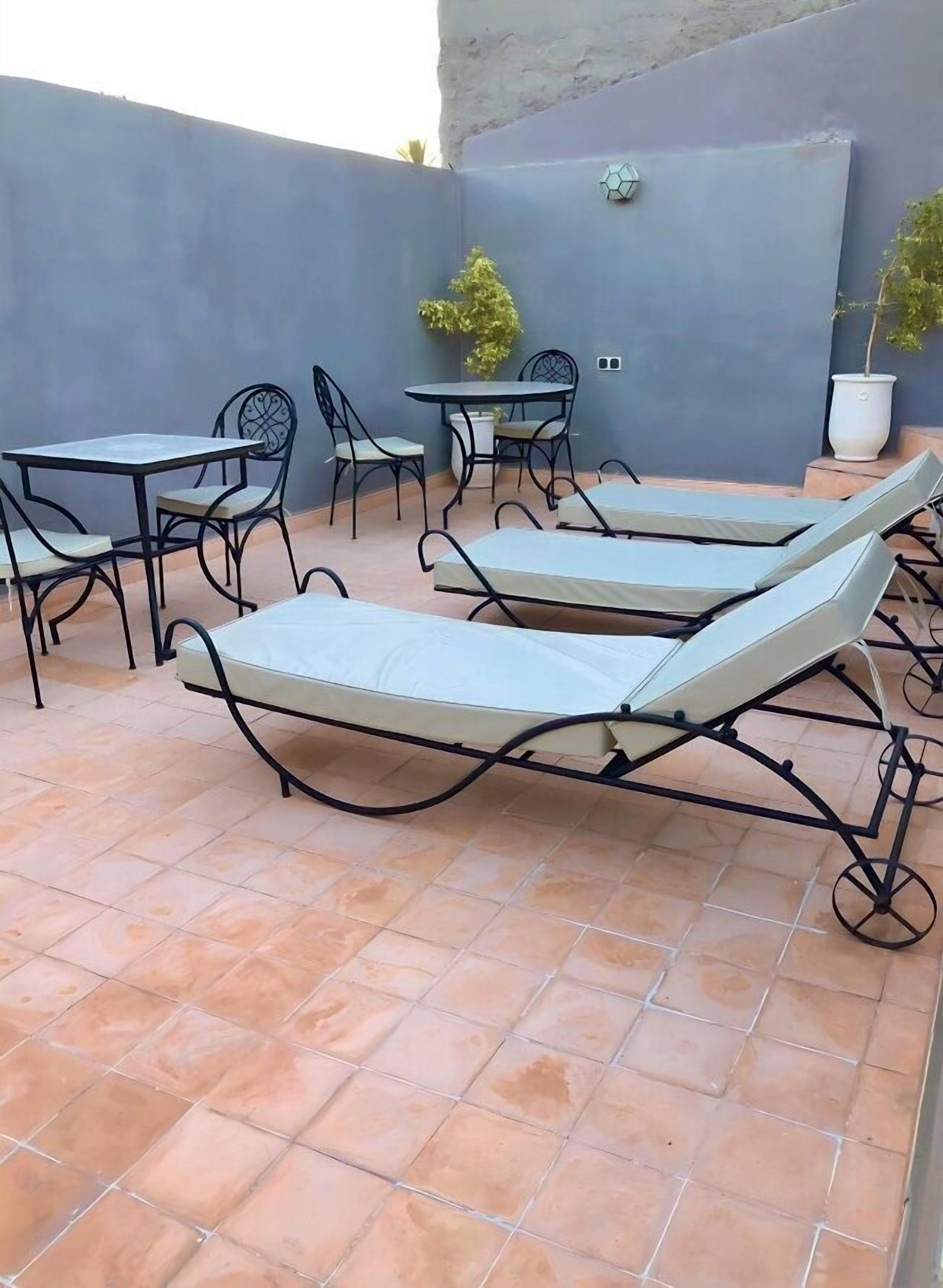 A patio with two sun loungers, a table, and chairs.