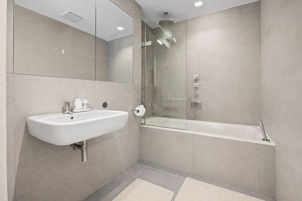 Une salle de bain moderne avec un lavabo, un miroir et un espace douche.