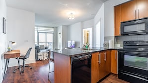 A modern kitchen with wooden cabinets, a built-in oven, and a microwave. - RS Suites - City Centre (Mississauga)