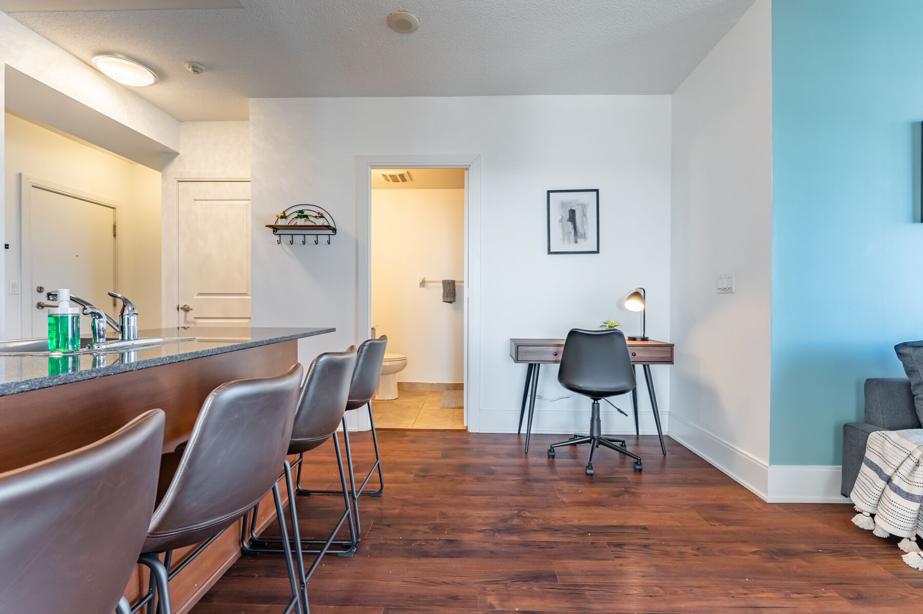 A modern apartment with a kitchen, dining area, and a small office space.