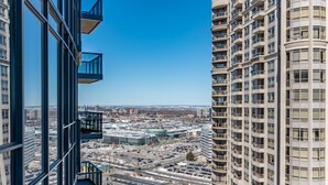 Un immeuble de grande hauteur doté de nombreux balcons, offrant une vue sur le paysage urbain, et un espace de stationnement où la neige recouvre le sol.