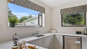 A modern kitchen with a built-in dishwasher, a sink, and a window with a view of the outside. - Rose Cottage - Lake Coleridge Holiday Home (Lake Coleridge)
