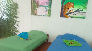 Two single beds with green and blue bedding, a large potted plant, and two framed pictures on the wall. - Amazon Nativo Lodge (Indiana)