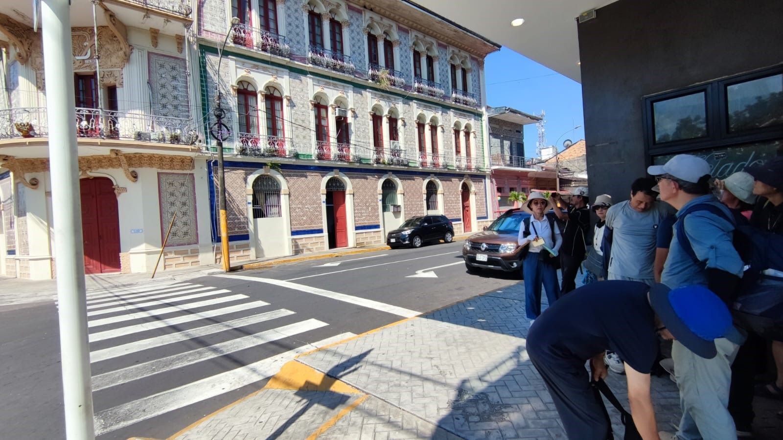 A street view with a building featuring ornate balconies and a crosswalk.