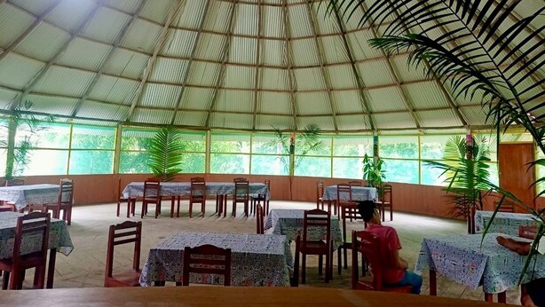 A covered dining area with tables and chairs, large windows, and potted plants. - Amazon Nativo Lodge (Indiana)