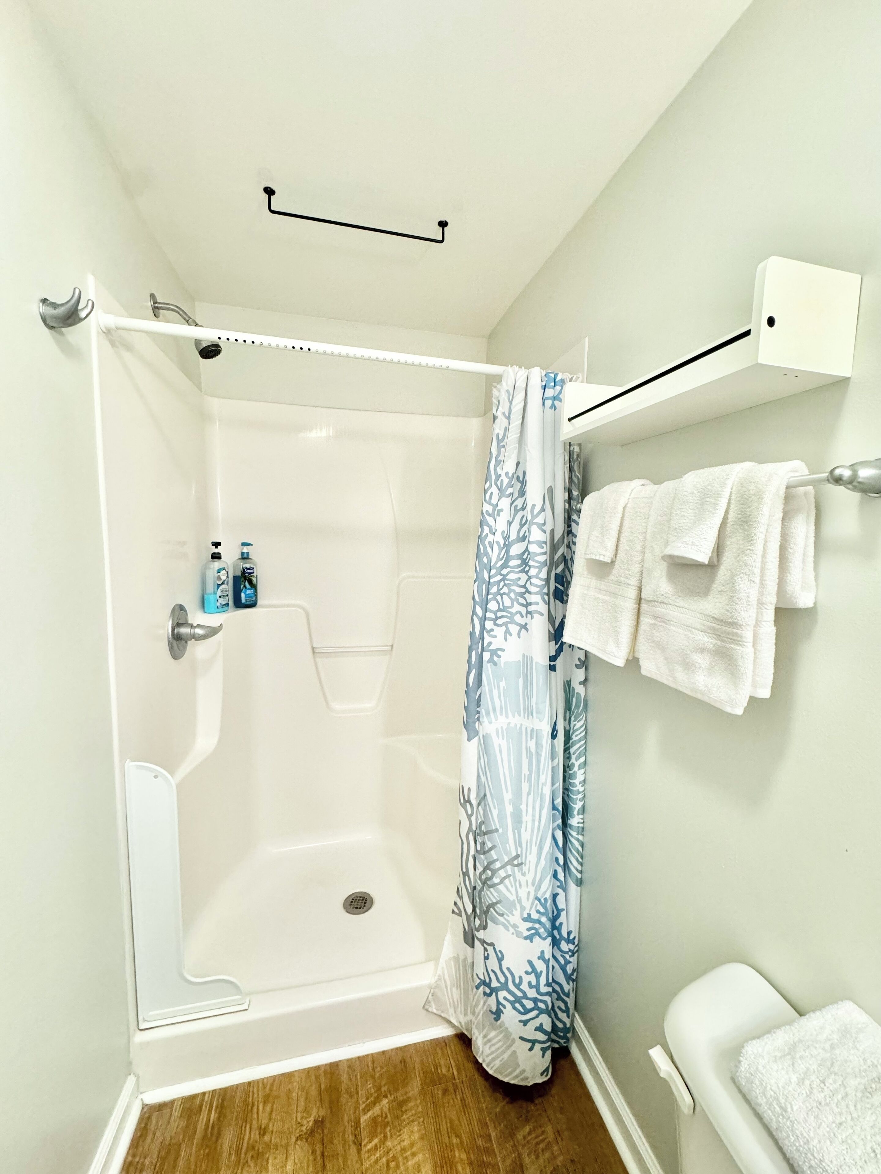 Une douche avec une baignoire blanche, un rideau de douche bleu et un porte-serviettes blanc avec des serviettes.