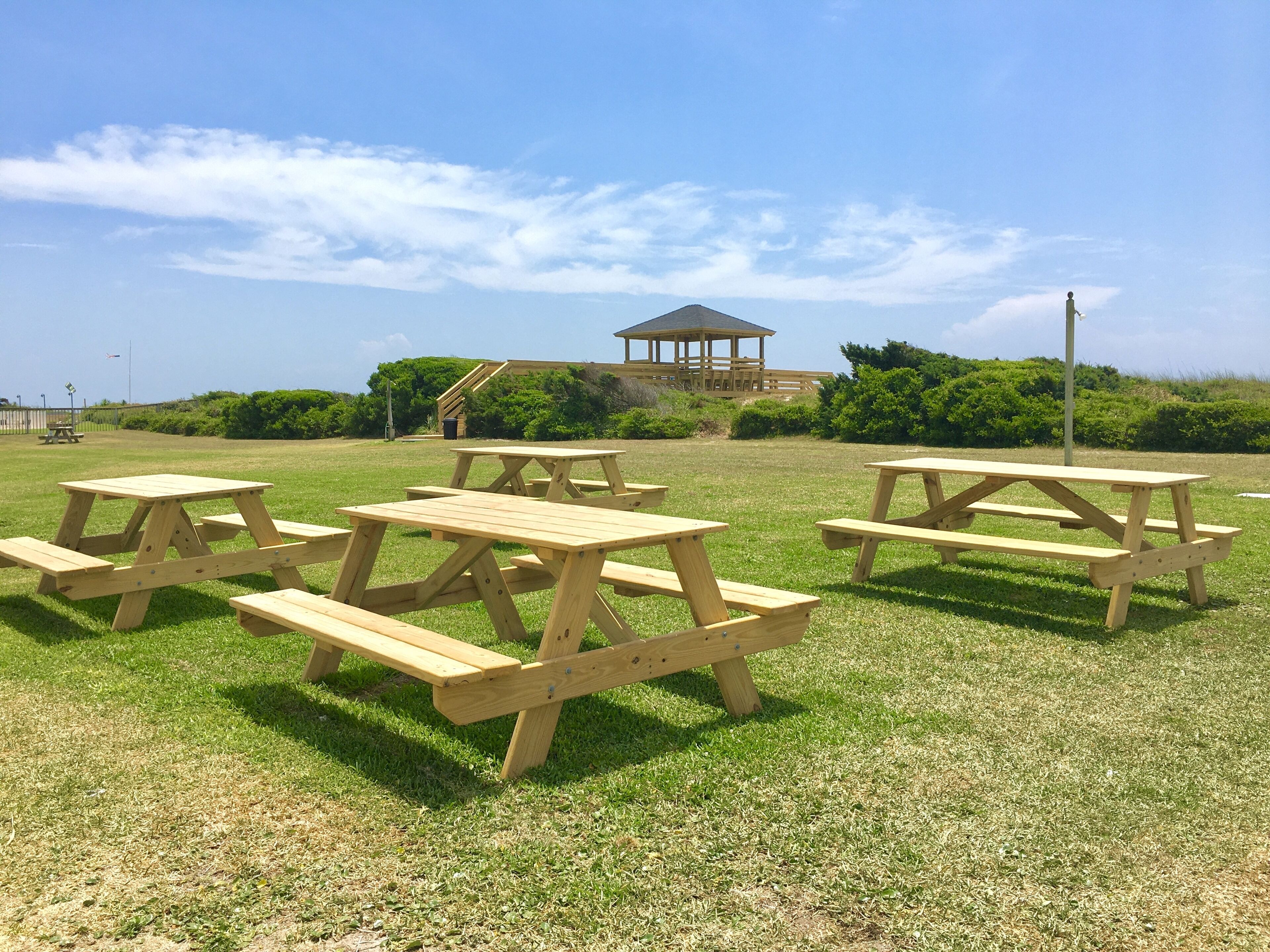 Picnicområde med træborde og bænke, en pavillon og en græsplæne.