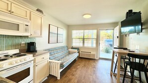 A kitchen with a stove, microwave, and a bench. There is a dining area with a table and chairs. - 1st Floor Coastal Escape • Direct Beach Access • Pool • Kitchen • BBQ Grills (Atlantic Beach)