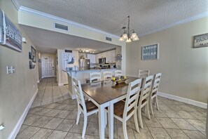 Une cuisine spacieuse avec des meubles blancs, un îlot central et un coin repas comprenant une table et des chaises en bois.